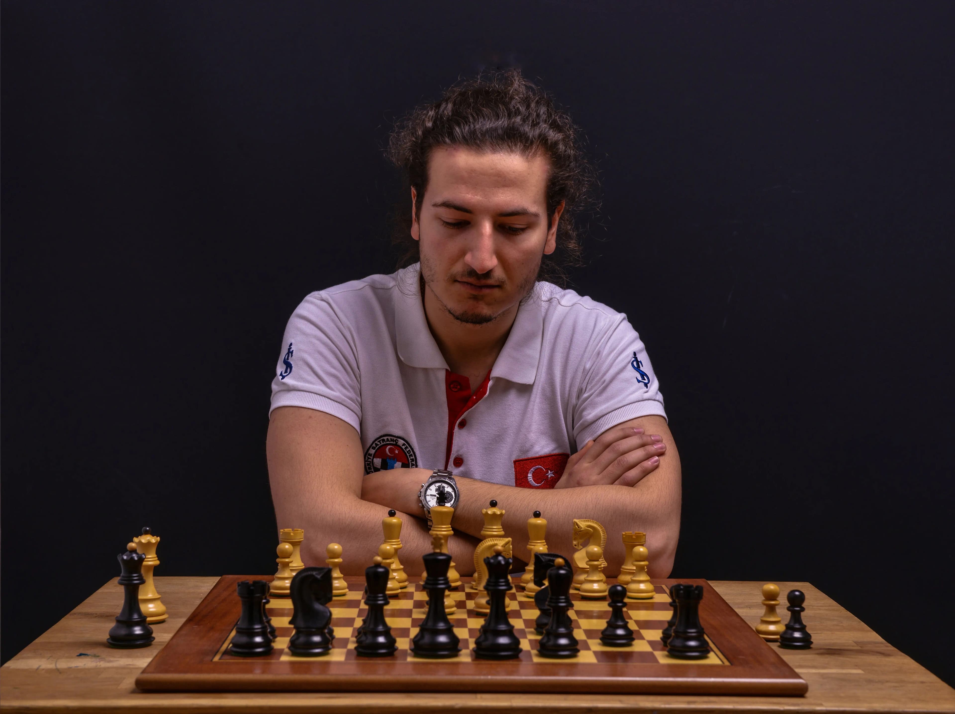 International Master Serkan Soysal at the chessboard, arms crossed, studying the position